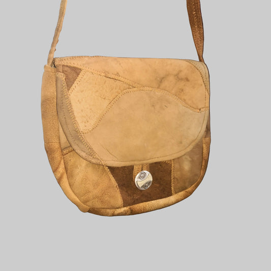 A brown amadou patchwork handbag with a shoulder strap, displayed against a white background